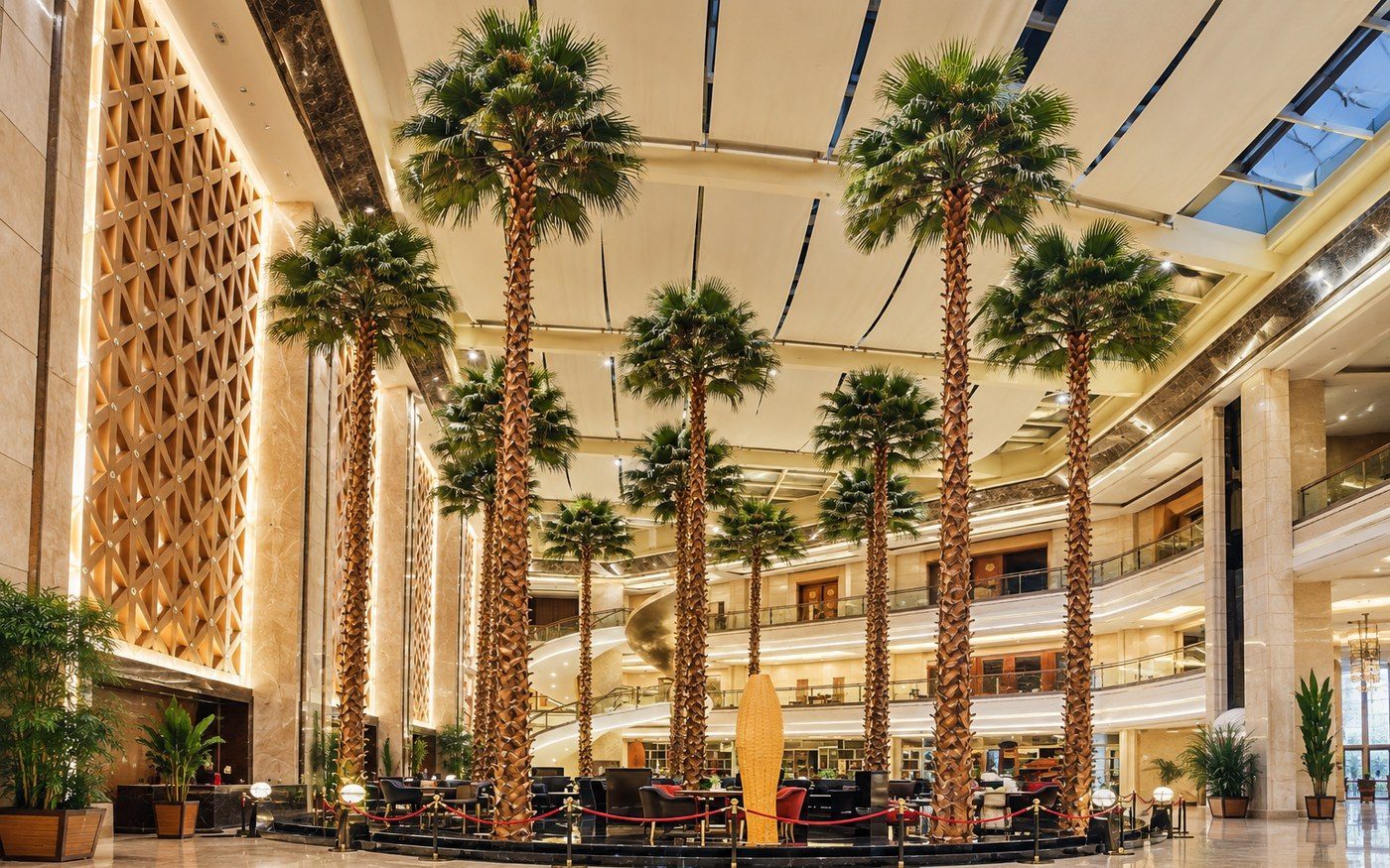 Row of six-metre artificial palms forming a colonnade across a shopping mall atrium