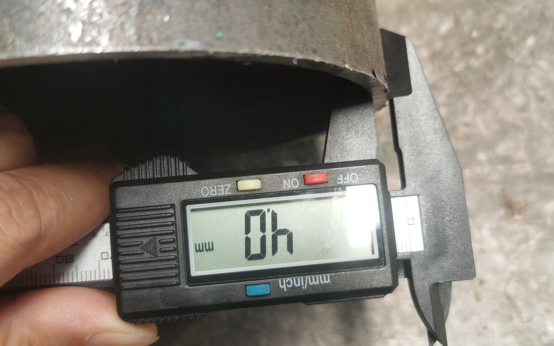 Digital calliper measuring the wall thickness of a galvanized steel pipe