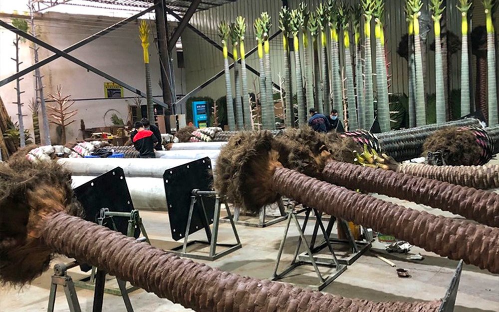 Palm trunk pieces on fabrication stands with steel base plates fitted at the trunk ends