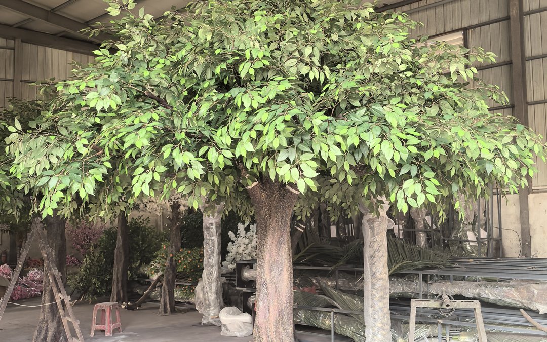 Large artificial ficus trees at different production stages inside the workshop