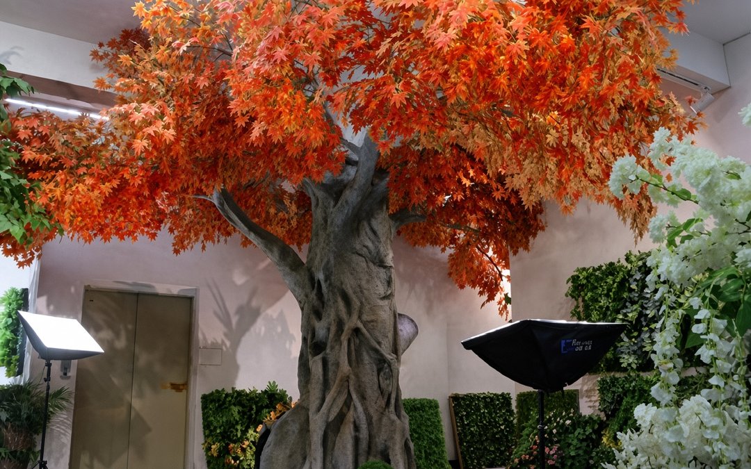 Autumn maple artificial tree with orange foliage displayed under studio lights in a showroom