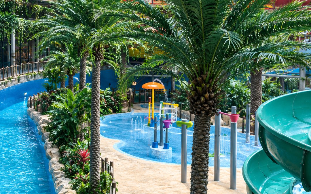 Artificial palms around a themed waterpark pool with slides and play structures