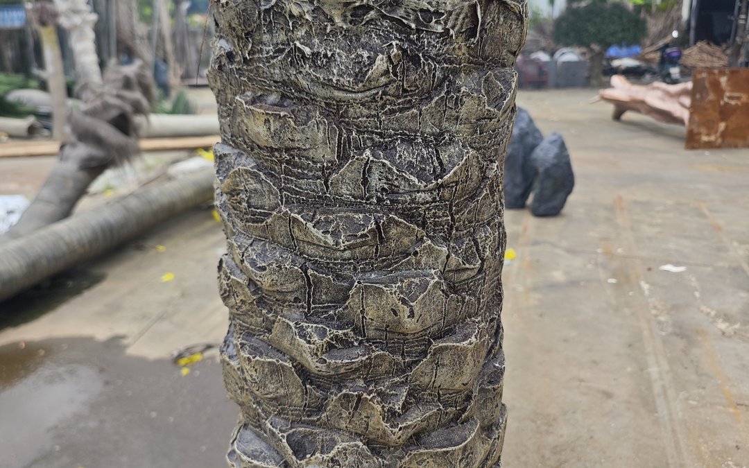 Moulded date palm trunk shell staged in the yard with further trunks in transit wrap behind