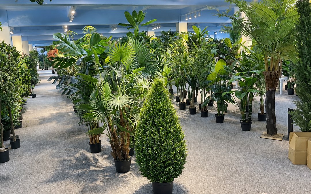 Showroom lineup of mixed artificial plant species on a base-plate floor