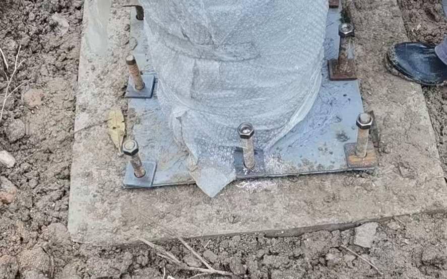 Galvanized base plate fixed with threaded anchor bolts on a concrete foundation pad
