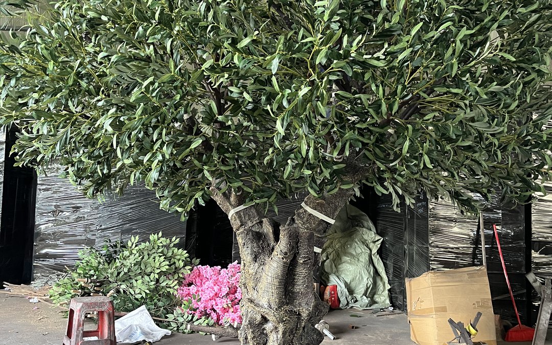 An artificial olive tree in a packing bay with trunk and branch junctions visible before wrapping
