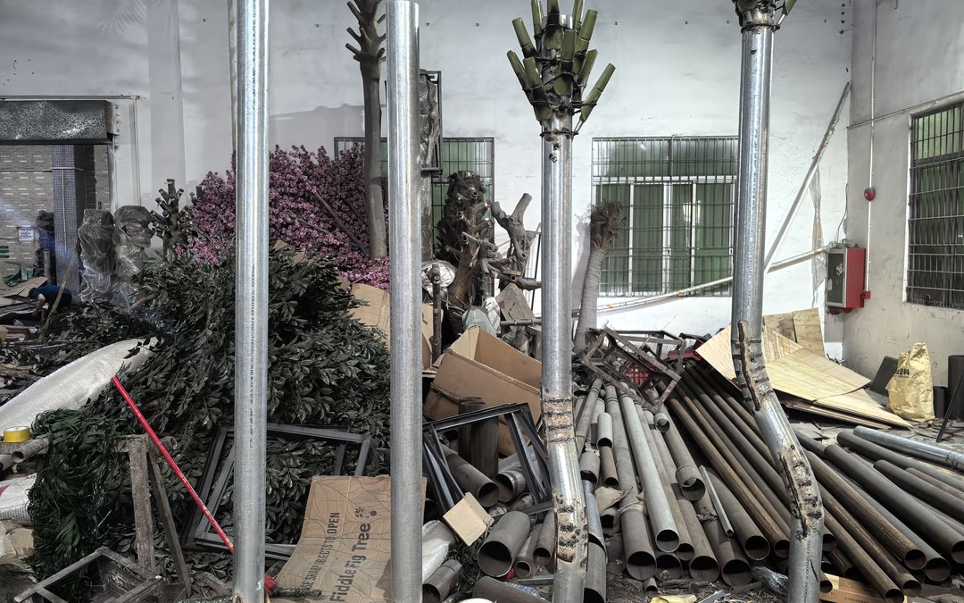 Galvanized cores standing in a workshop yard among cartons and foliage