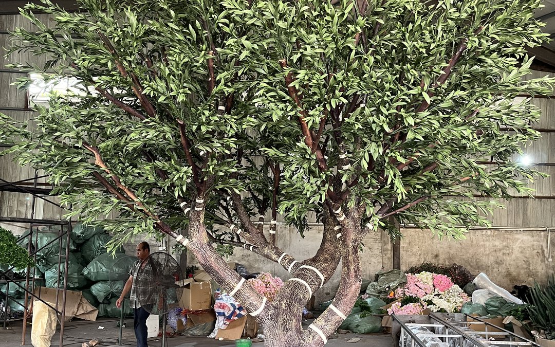 Large artificial olive-style tree with trunk and branches wrapped in protective mesh in the workshop