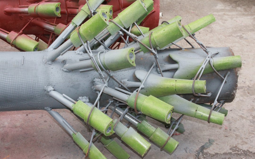 A grey glass-reinforced trunk with green branch sockets welded onto steel rods and tied with wire