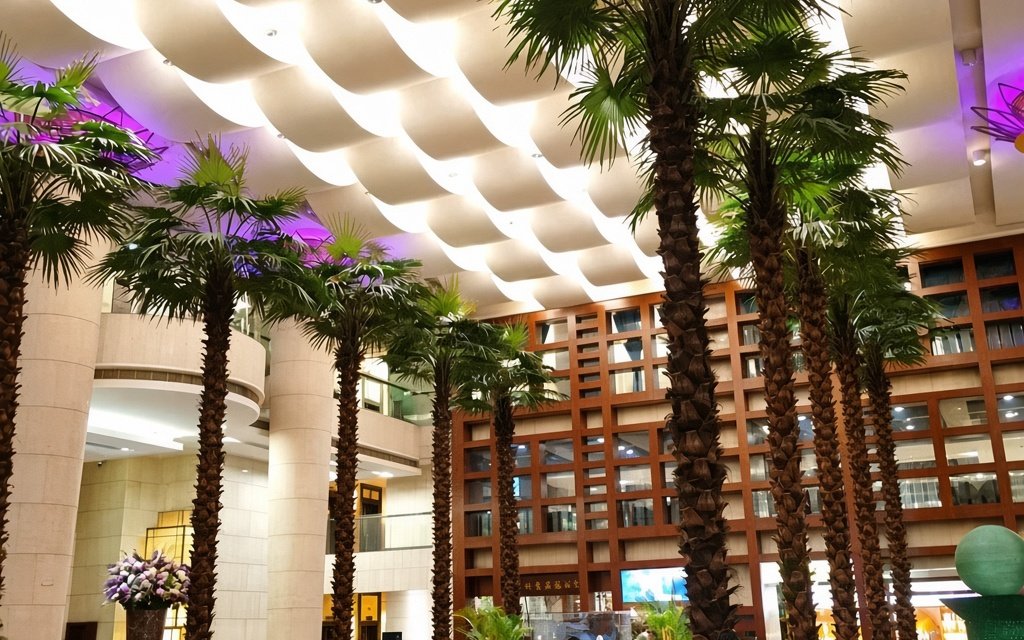 Indoor specification palms in a shopping mall atrium with fronds clearing the ceiling services