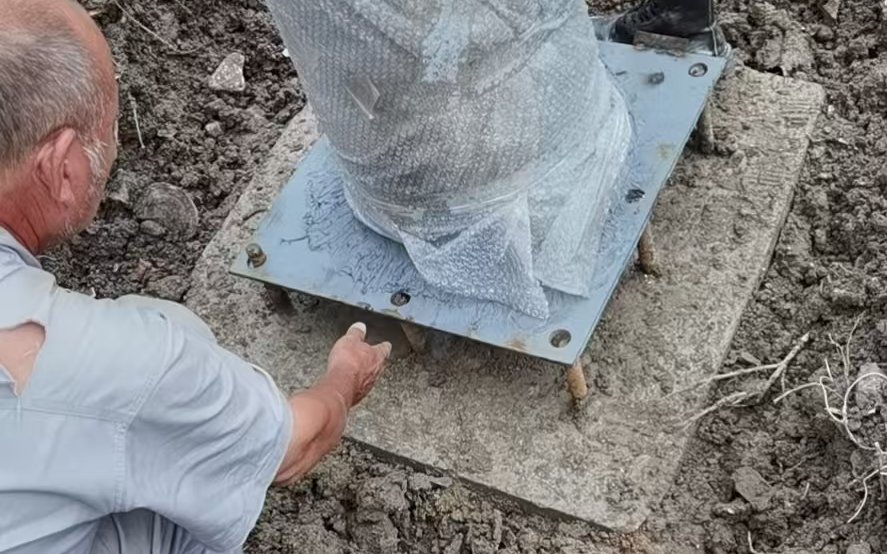 Base plate aligned under a trunk base on prepared ground during installation