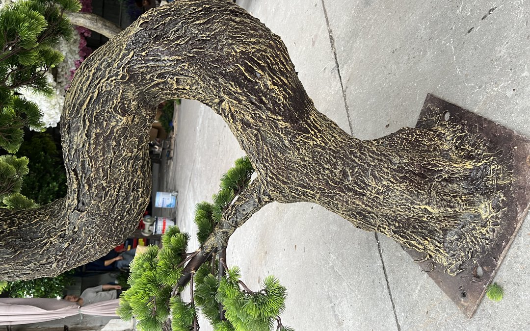 Moulded bark texture on a curved trunk landing on a steel base plate