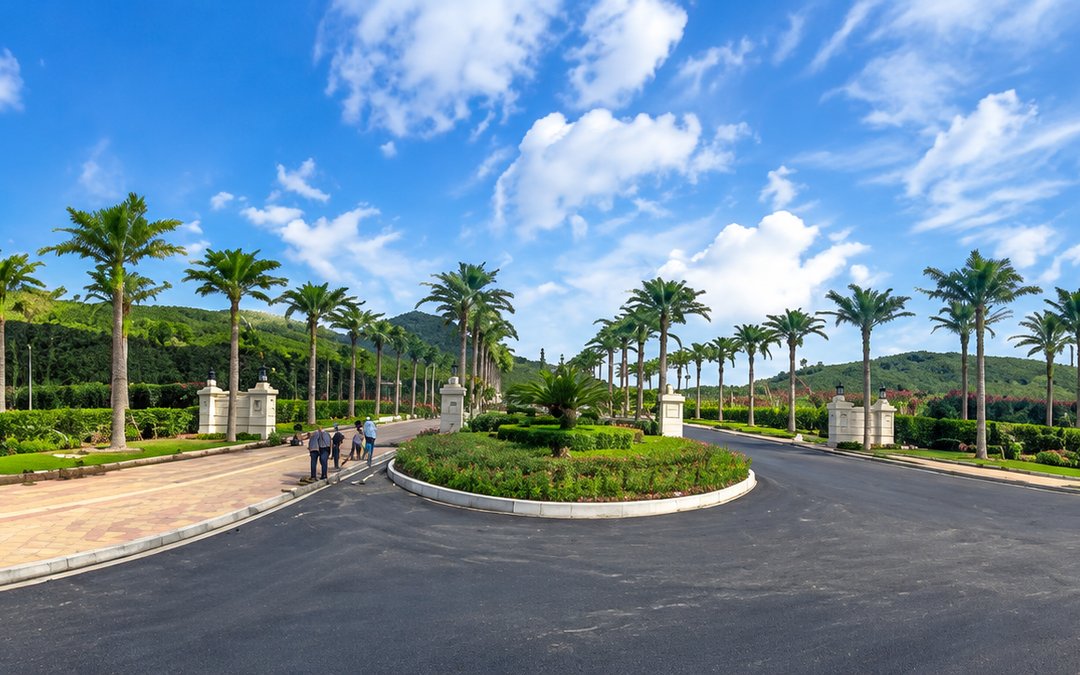 Date palms lining a gated estate entrance road between stone gate piers