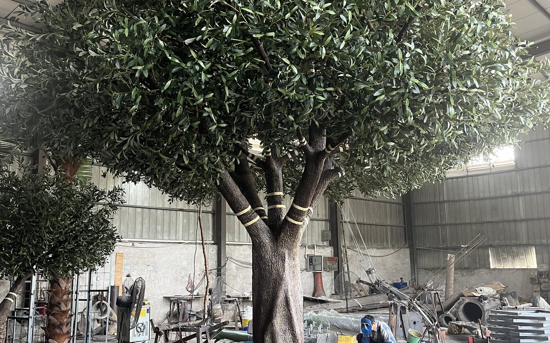 Large artificial tree standing in the factory bay during assembly, trunk banded and labelled