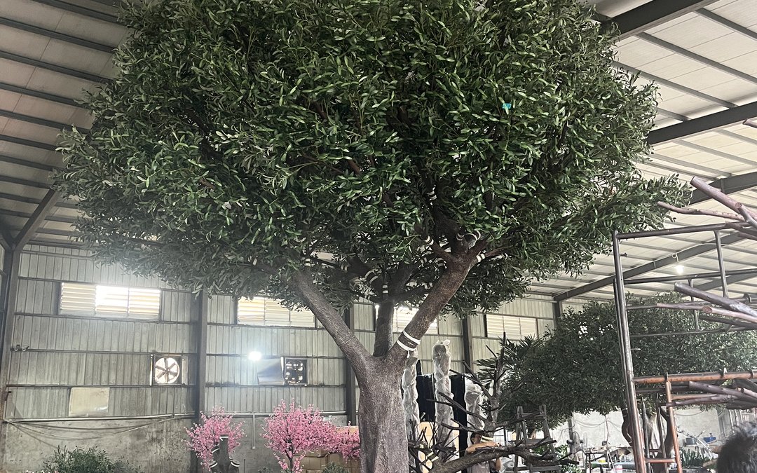 Large canopy build under final dressing in the production hall, trunk still banded, blossom trees staged behind