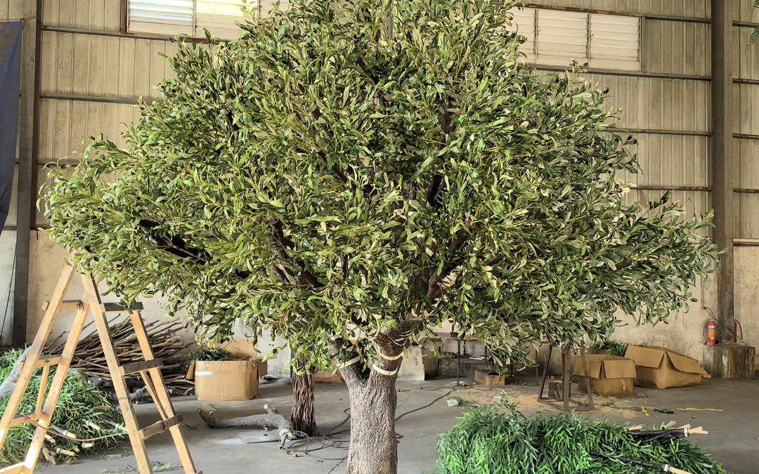 How water and salt spray attack outdoor artificial trees: base drainage, cut-edge protection, fixing grades by ISO 9223 and the wet-season checks.