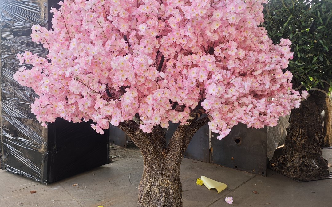 A pink blossom artificial tree standing in the dispatch area beside stretch-wrapped export pallets