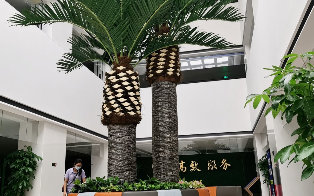 Two artificial date palms installed in planter boxes at a glazed reception