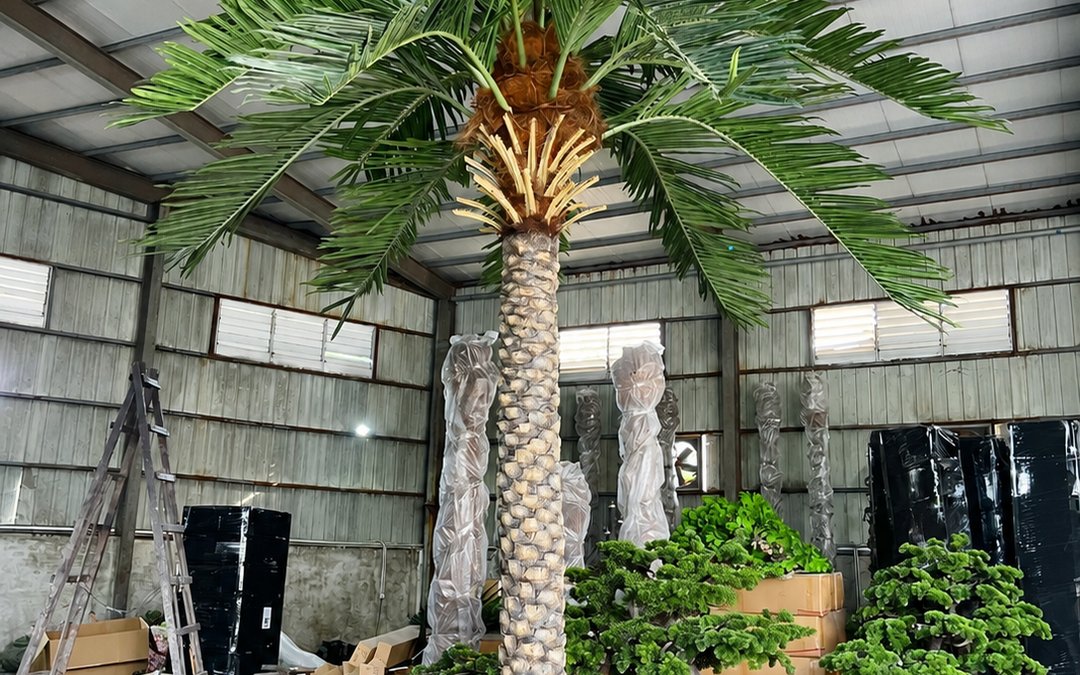Finished artificial palm staged in the production hall with neighbouring trunks in transit wrap