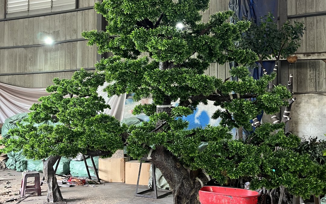 Large artificial trees standing inside a factory workshop on temporary steel supports