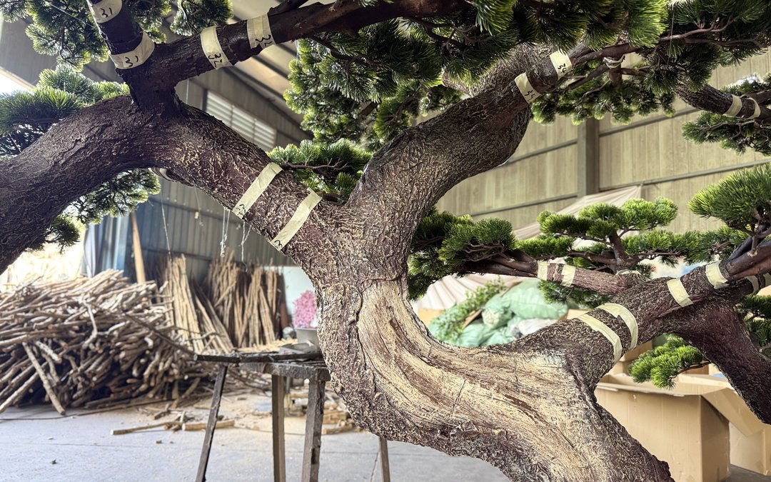 Large artificial tree trunk and branches in the workshop with numbered cloth tags tied to the branch positions