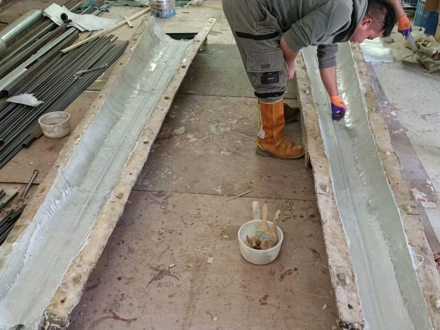 Workers hand-finishing the surface of an artificial palm trunk in the factory
