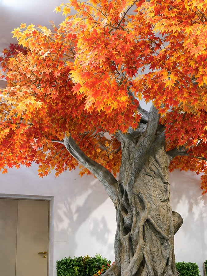 Artificial autumn maple tree with orange and red foliage in a showroom