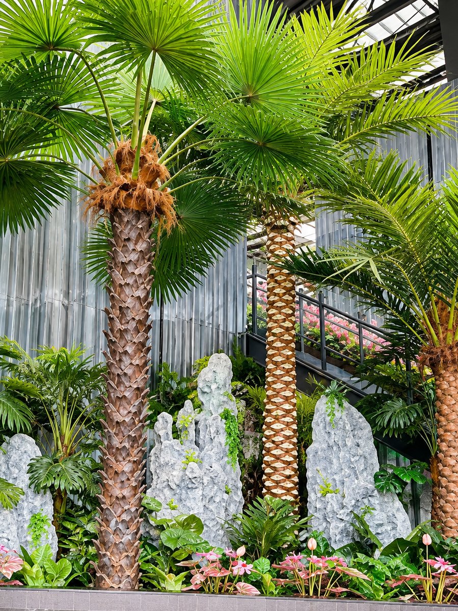 Artificial fan palms with a rockery planter bed in a glass atrium indoor garden