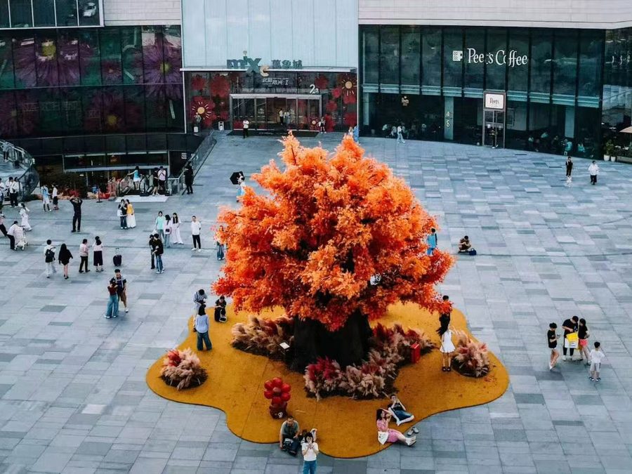 Large artificial maple tree with golden foliage installed in a shopping plaza