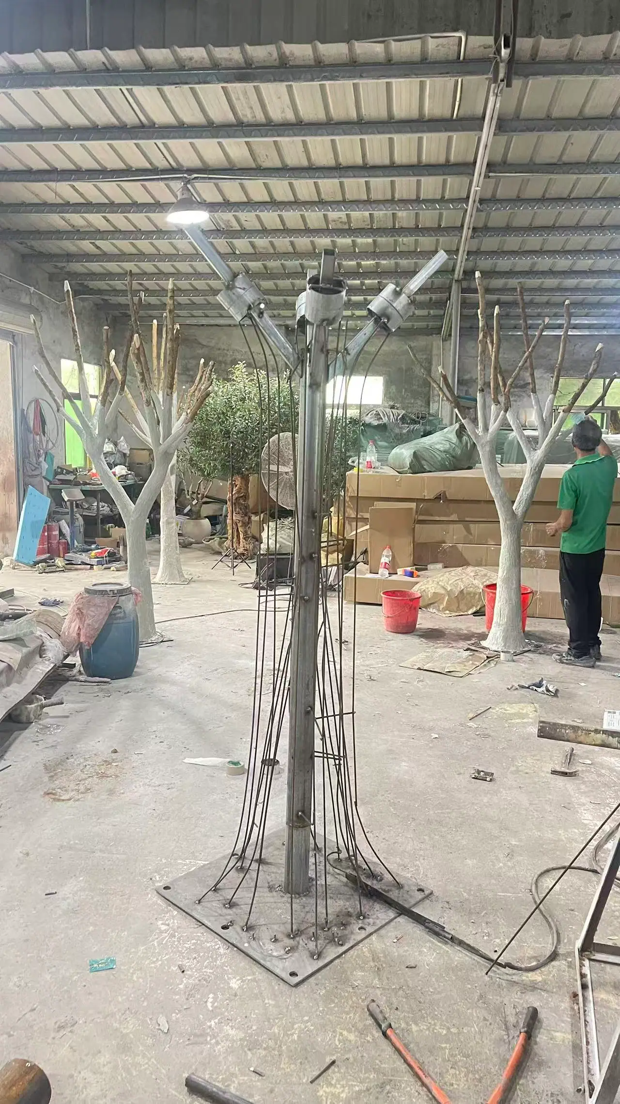 Two production workers lifting a carved artificial tree trunk section inside the Pure Faux Flora workshop